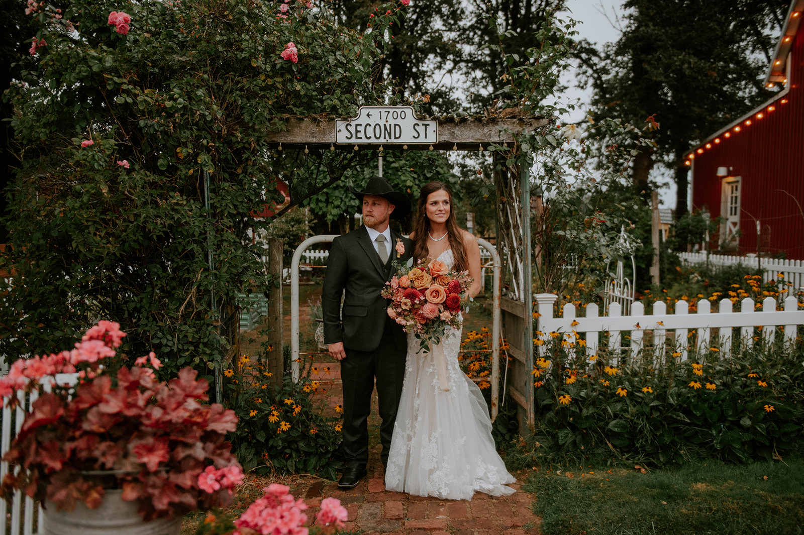 Bride and groom standing in front of the gate looking opposite directions at Vintage Gardens Rustic events 