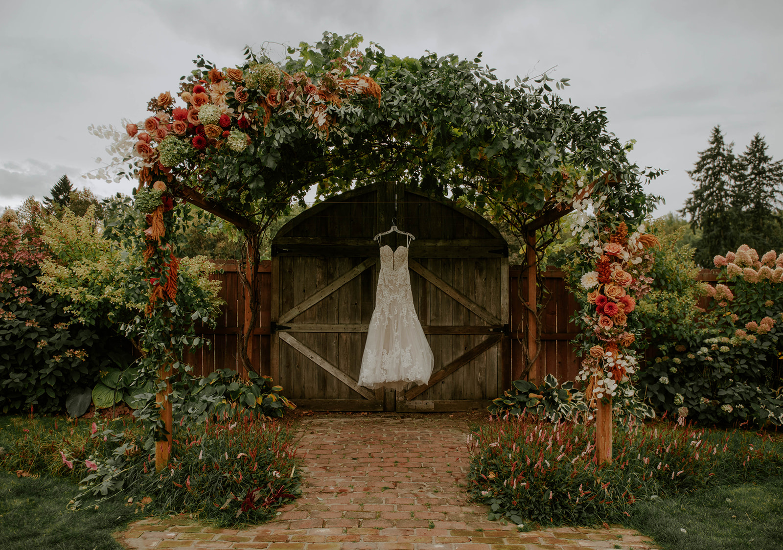 Wedding dress hanging around the flower arbor at Vintage Gardens Rustic Events