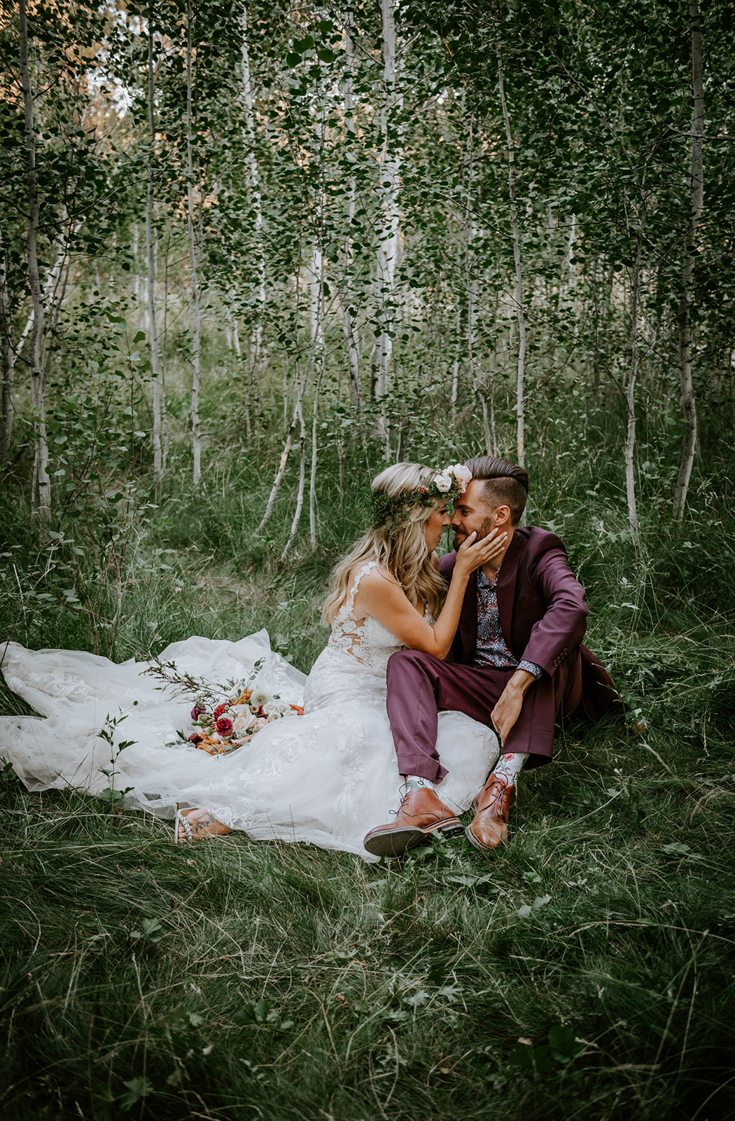 Bride and groom sitting on the ground and embracing in a grove of aspen trees at shevlin park 