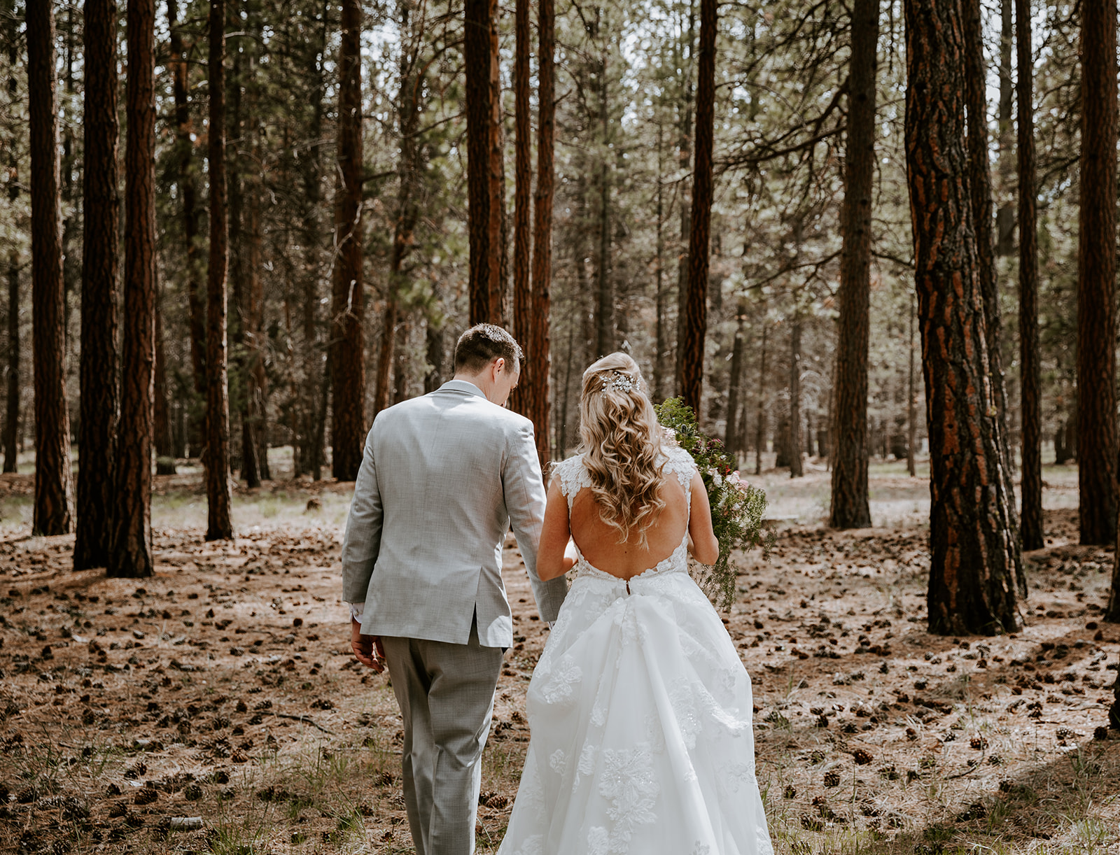 Bride and groom walking into the trees in sisters oregon
