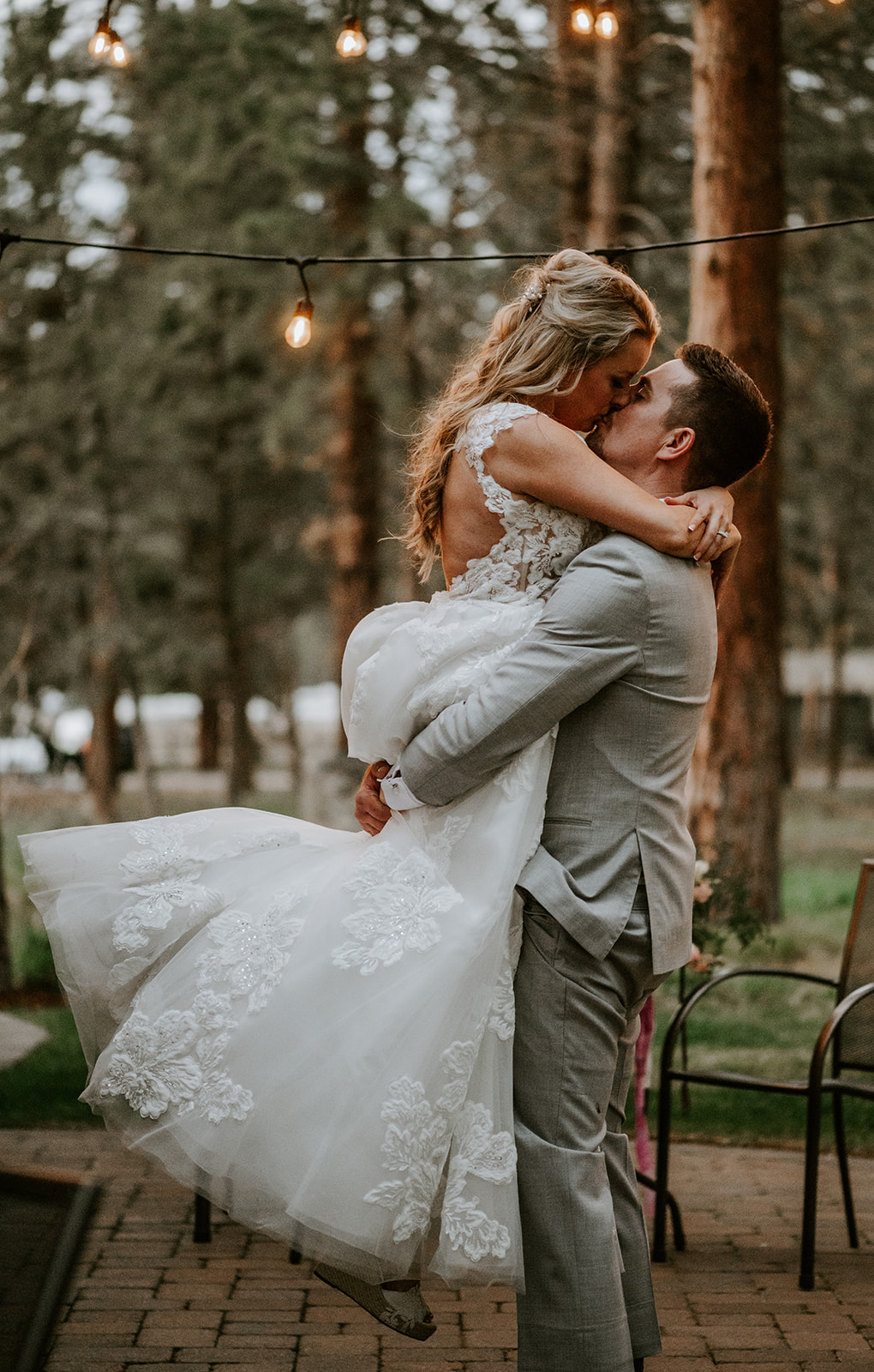 Groom lifting bride up and kissing her at their spring wedding