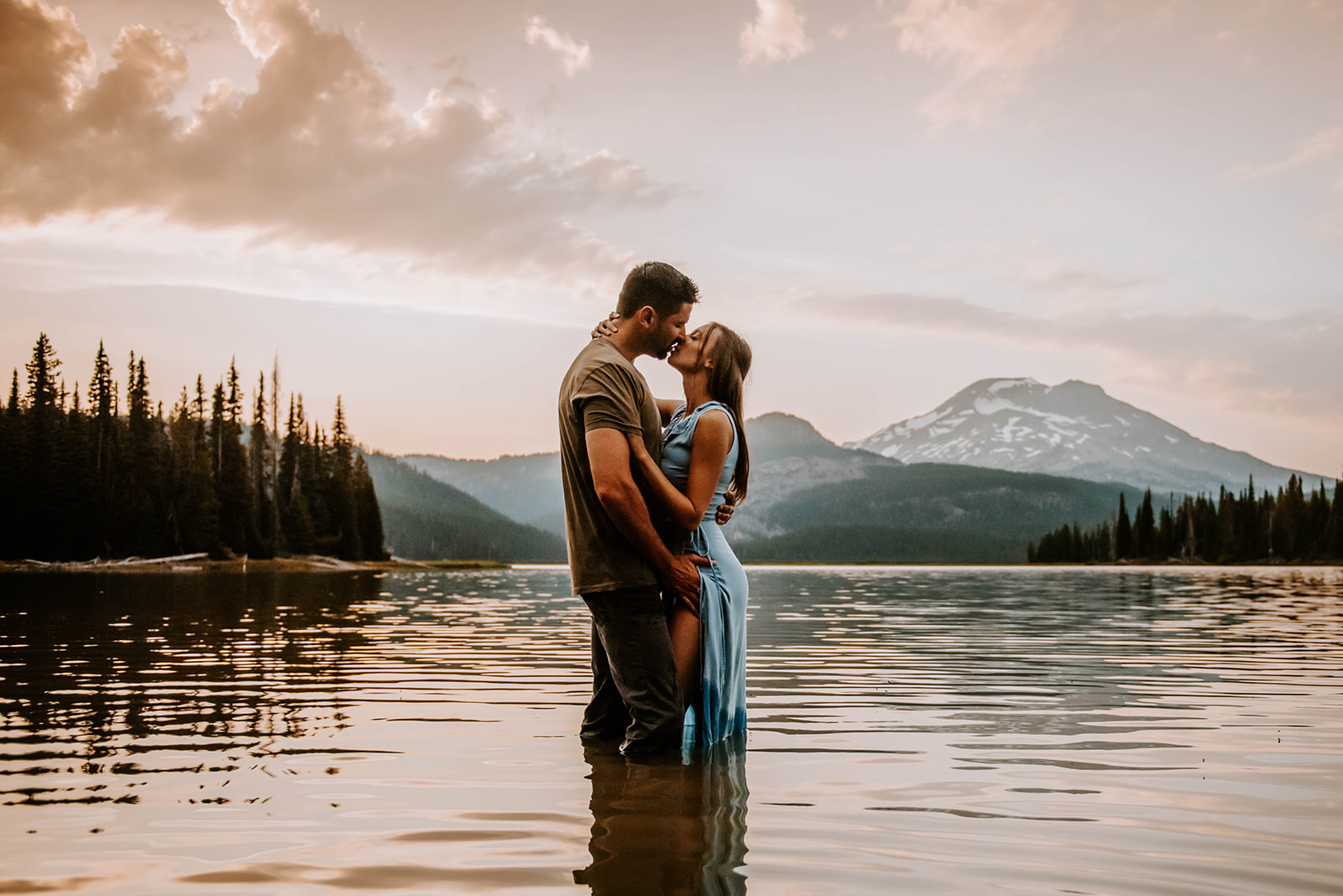 A couple standing in the water and kissing in front of the mountain at sunset at Sparks Lake just outside of Bend, OR.