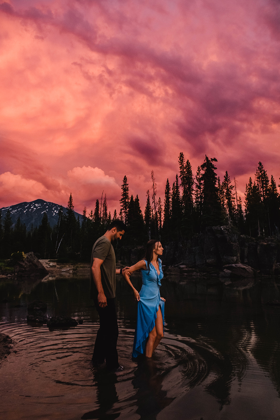 A couple walking through the water during a pink sunset at the base of Mt. Bachelor at Sparks Lake