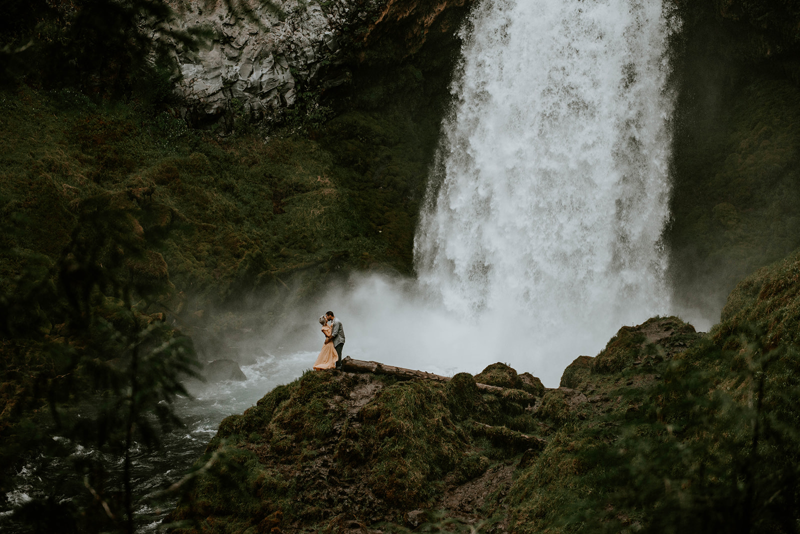 A couple dancing together at the base of Sahalie Falls for their engagement photos.