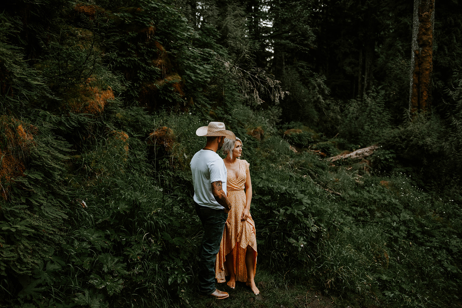 A couple posing for engagement photos in the forest 