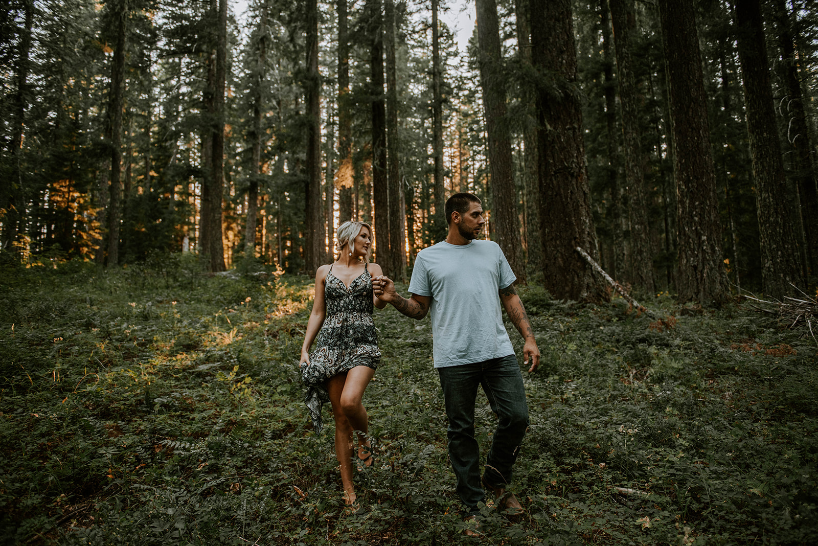 A couple walking through the lush forest together in Oregon during their engagement photos