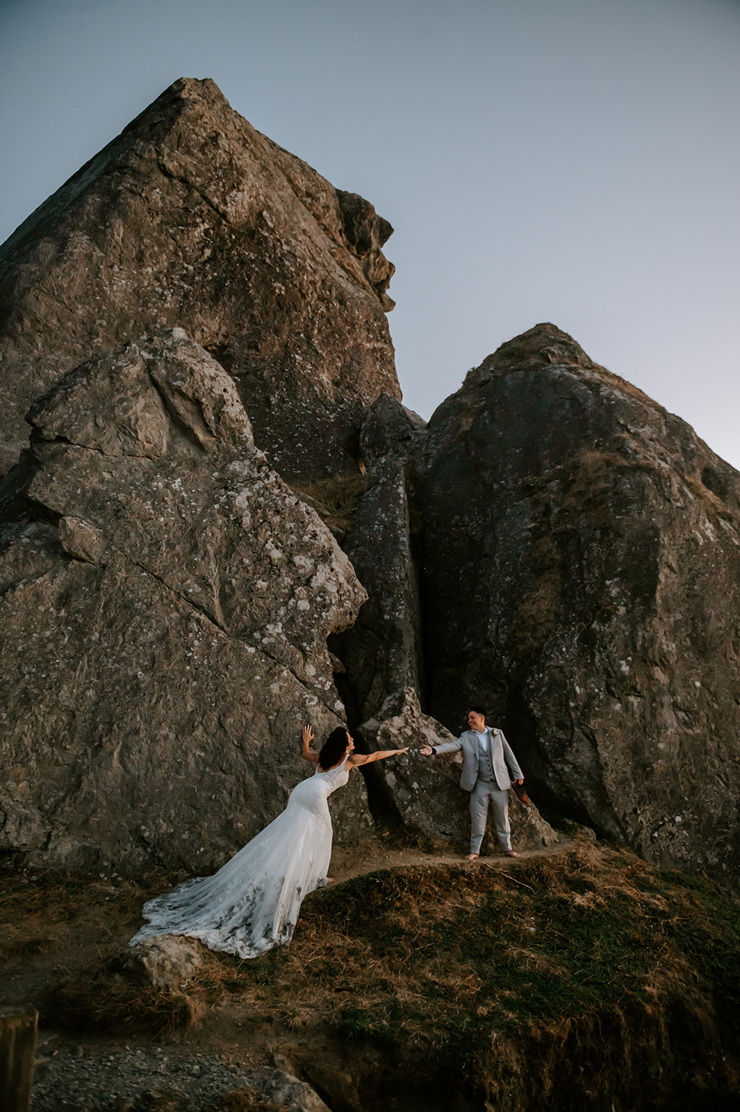 Two brides reaching for each other at kissing rock on the Oregon coast