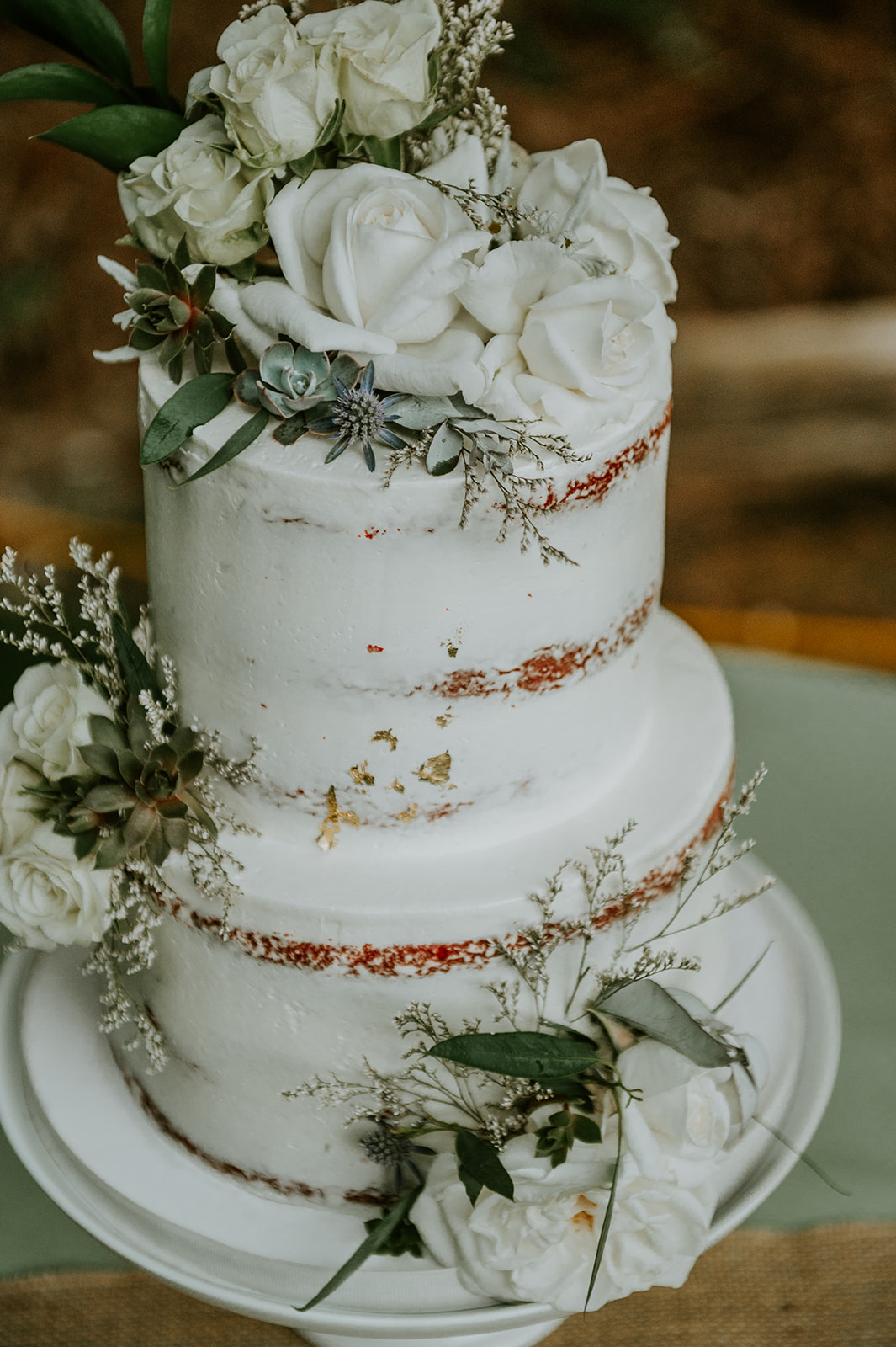 White, green, and gold wedding cake with white roses