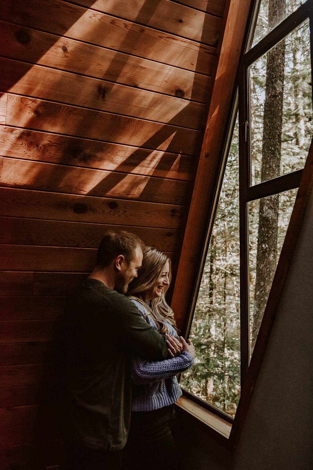 A couple looking out the window of a cabin in rhododendron oregon