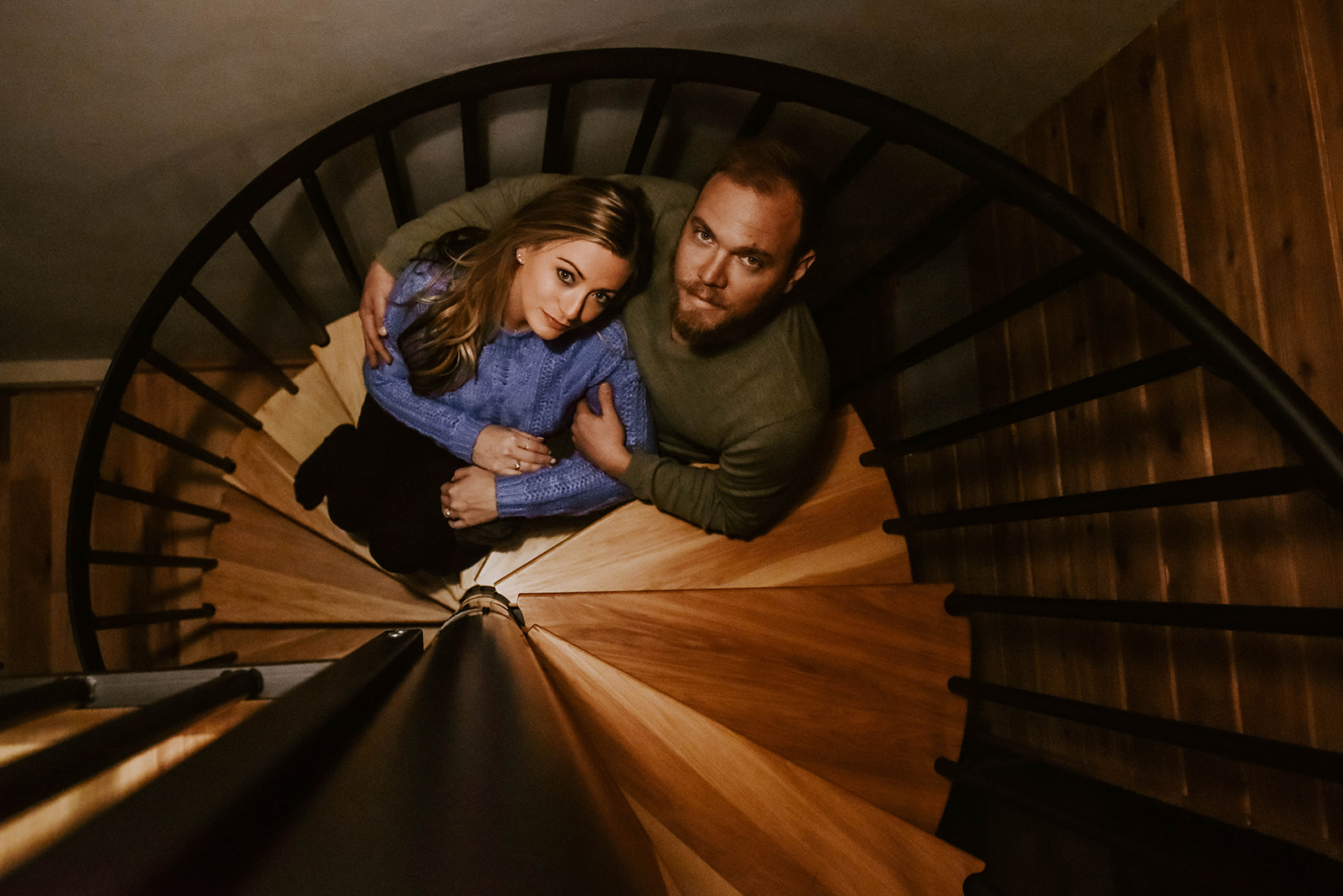 A couple sitting on a spiral staircase looking up