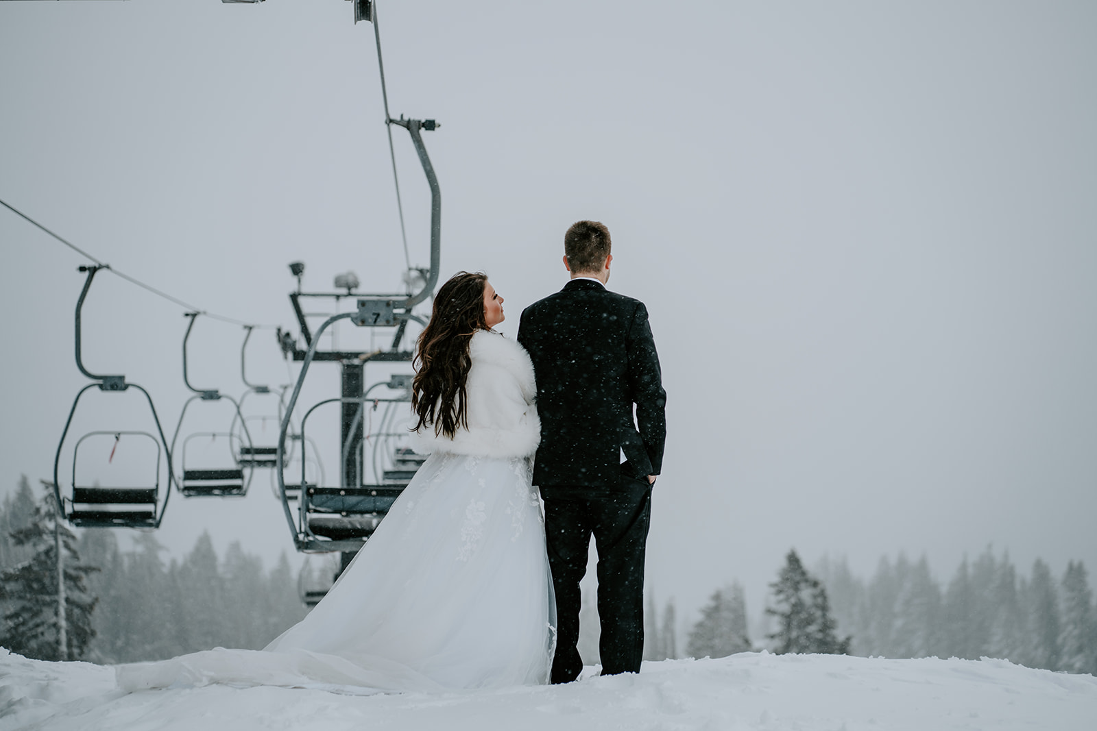Bride and groom at ski lifts at Timberline Lodge during a snowstorm on their wedding day.