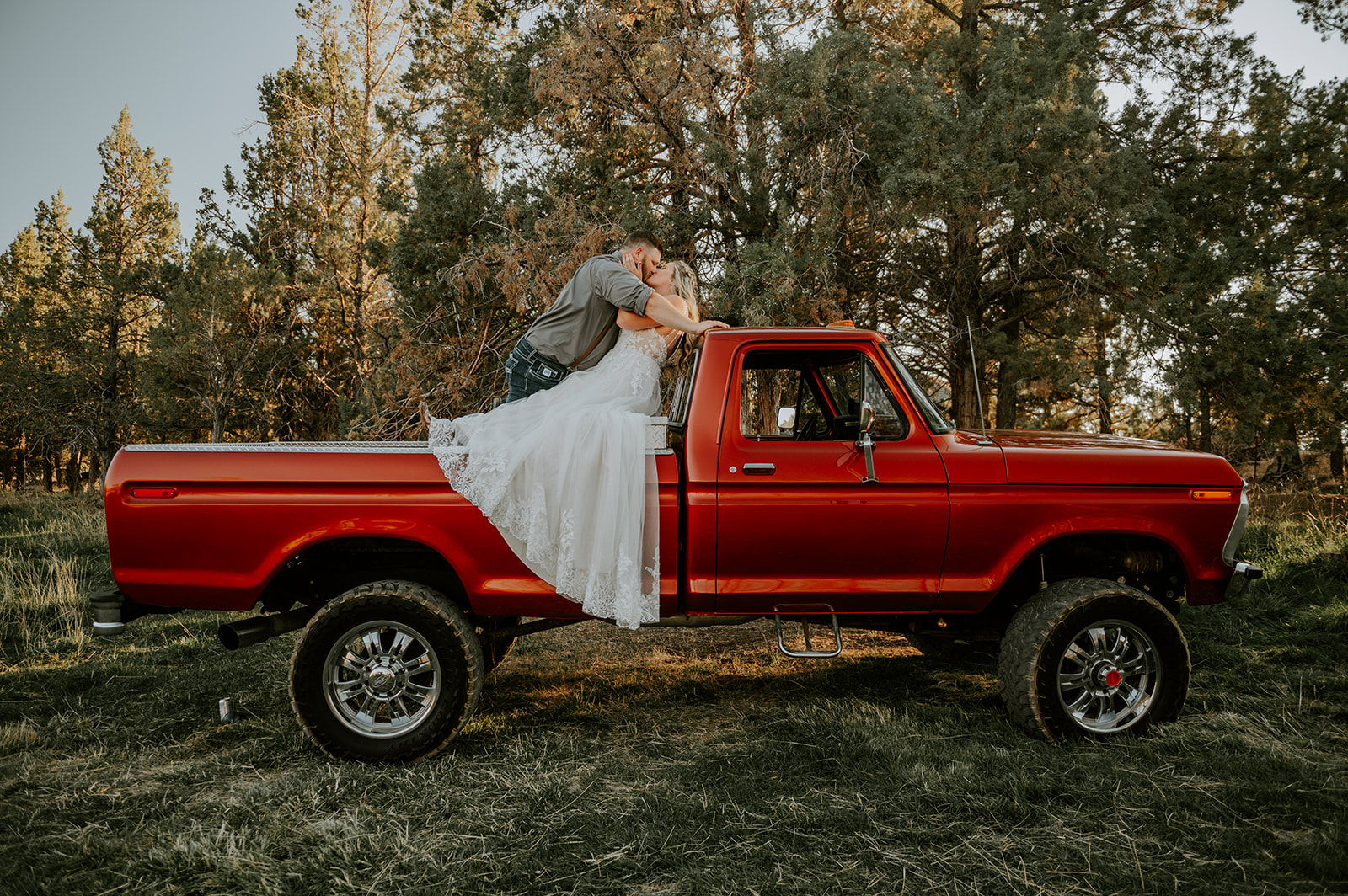 Bride and groom kissing in the bed of a vintage ford