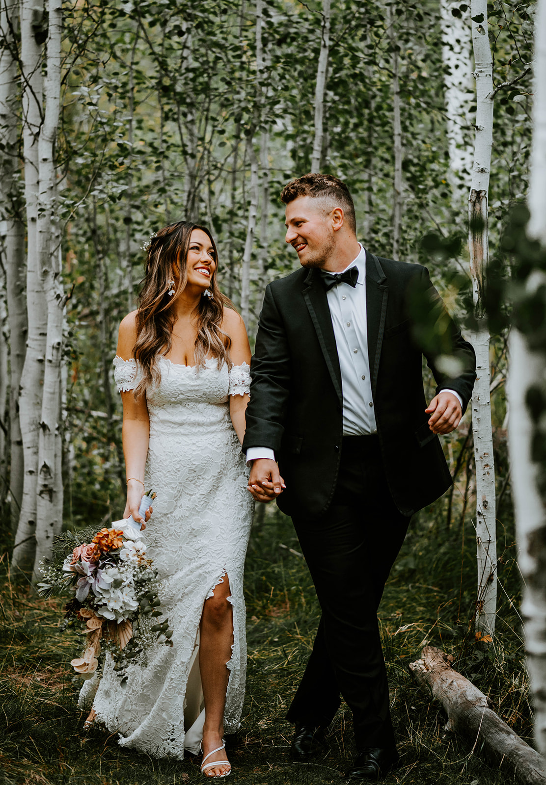 Bride and groom walking through the aspen trees at shevlin park together