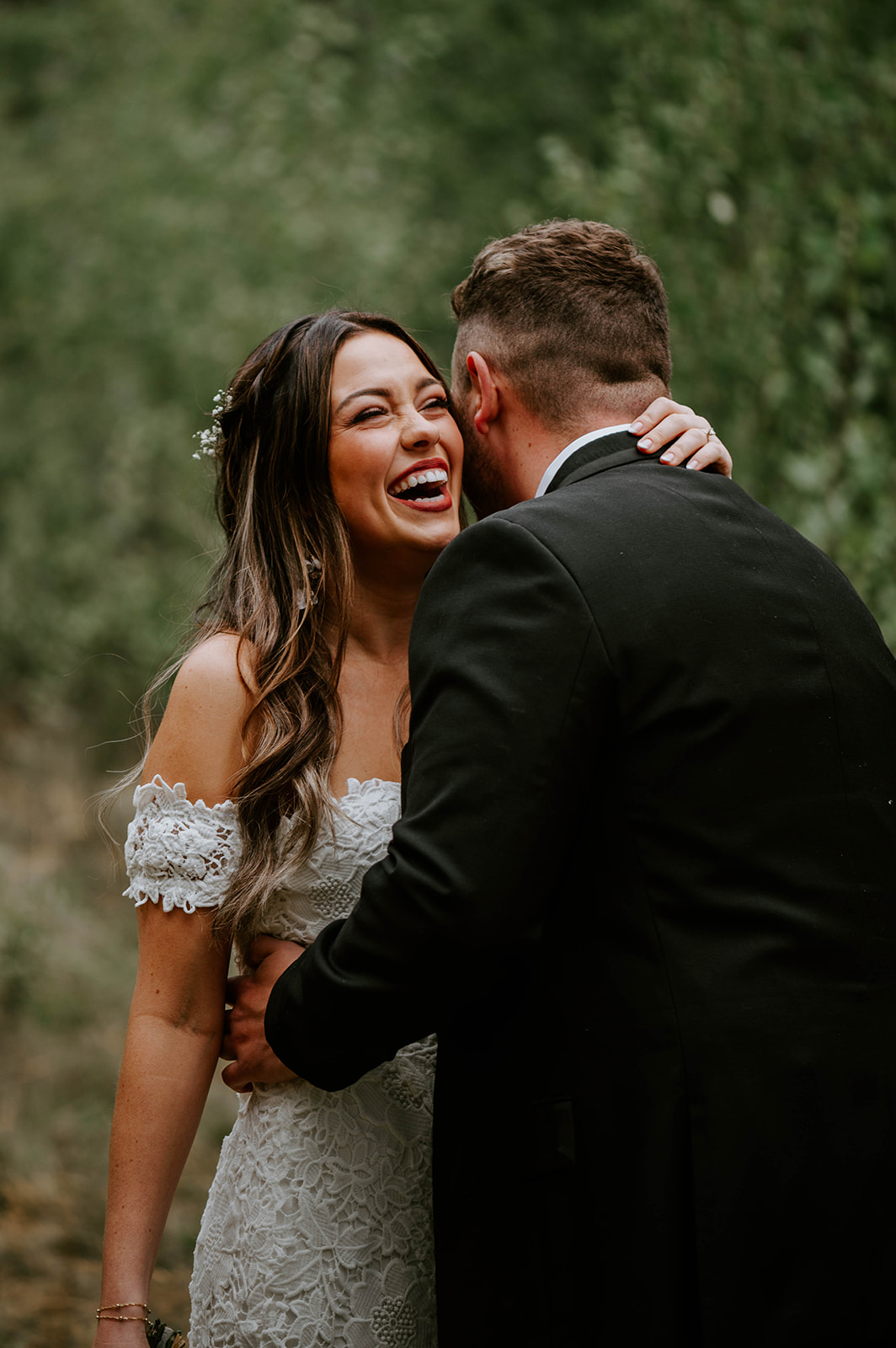 bride laughing over grooms shoulder at bend wedding
