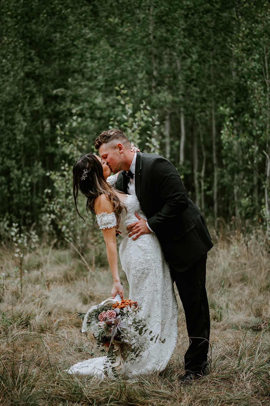 Groom dips and kisses bride in the aspen groves 
