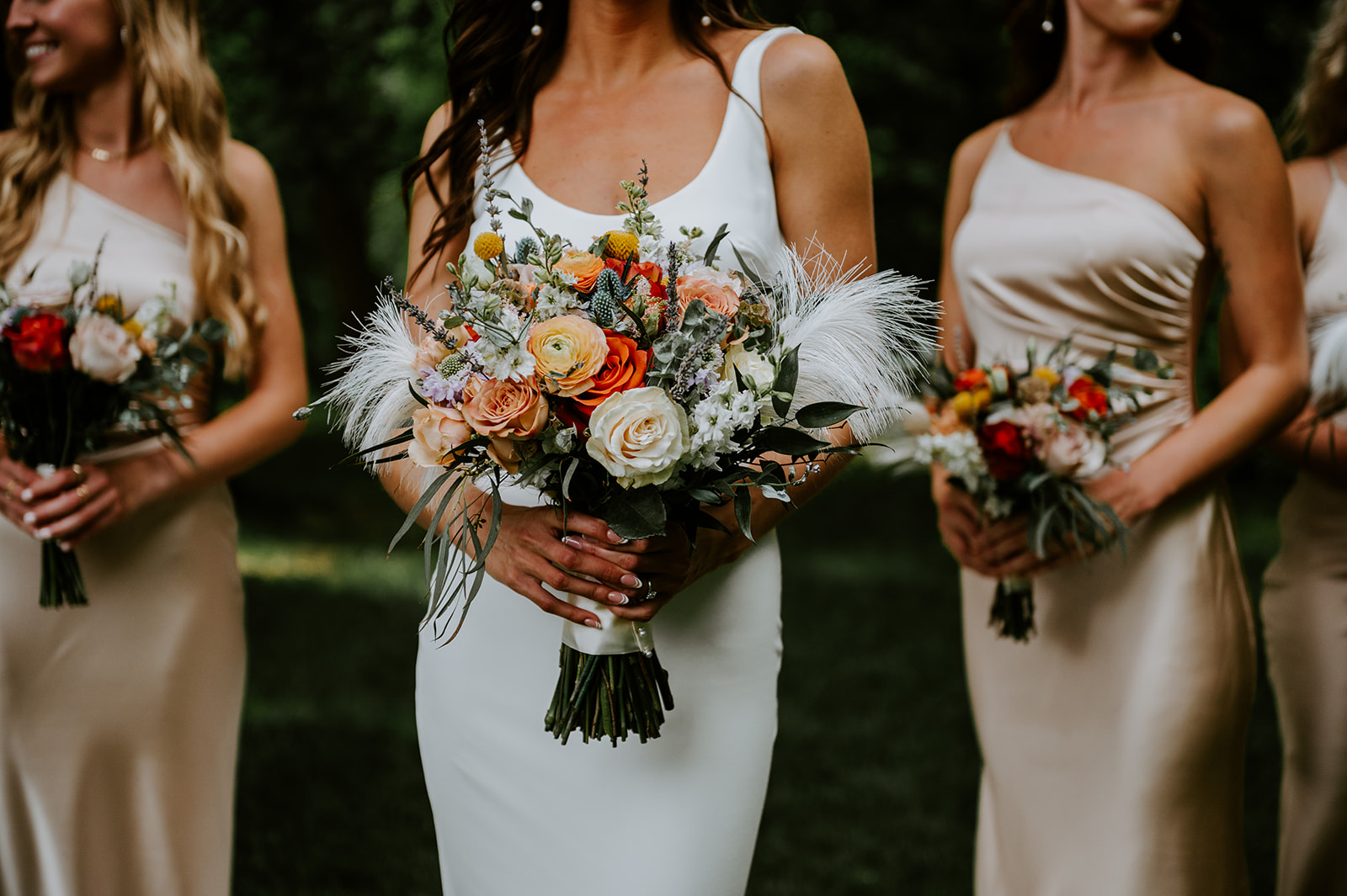 Bride and bridesmaids with colorful bouquets with ostrich feathers and beige dresses