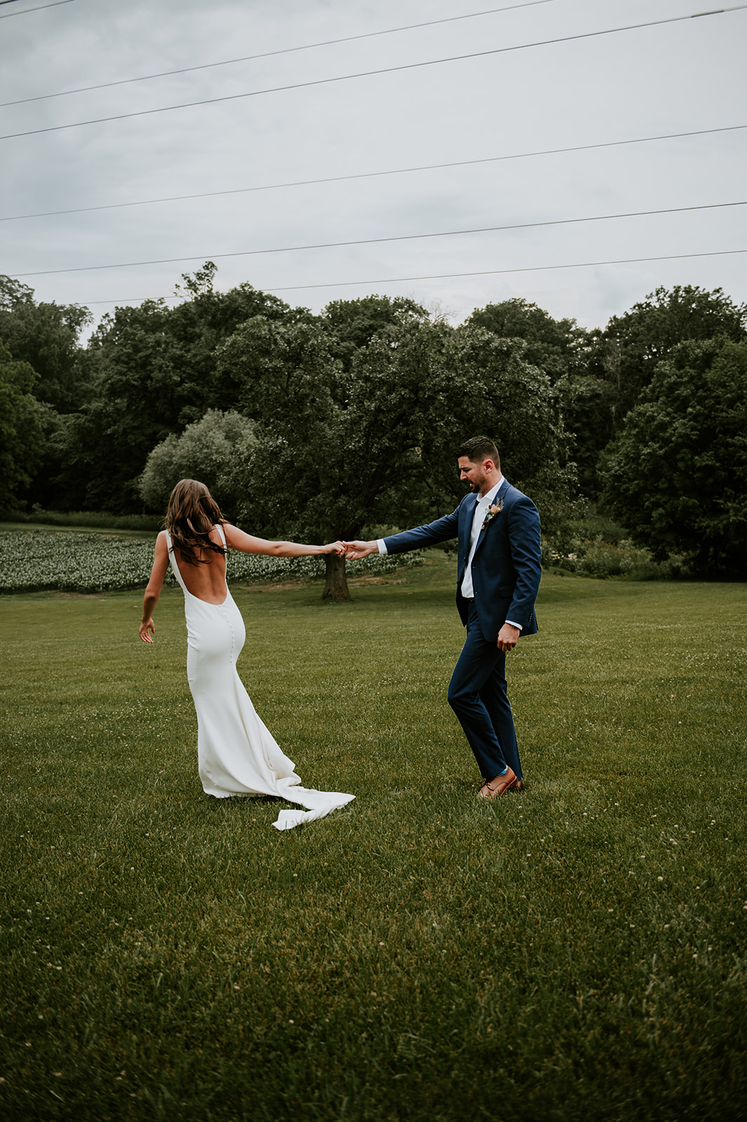 Groom spinning bride during first look in a field