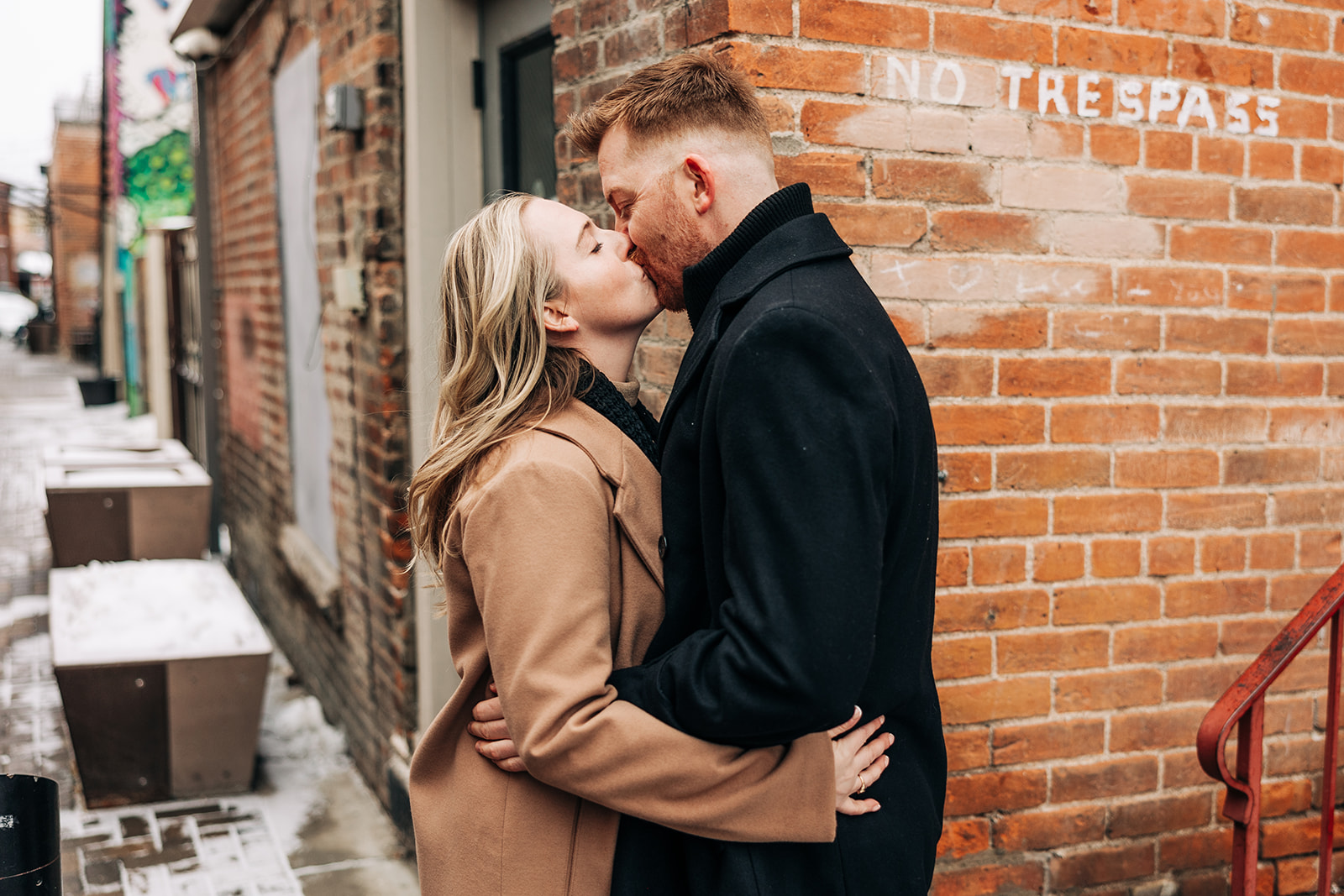 man and woman kissing next to a no trespassing sing