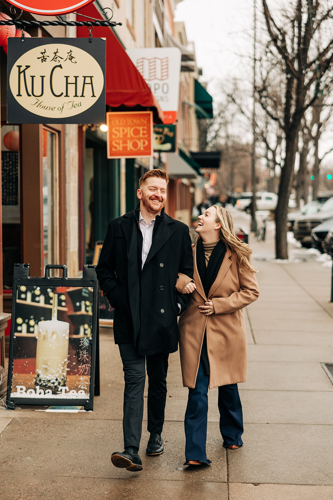 man and woman walking through Downtown Fort Collins for their engagement session