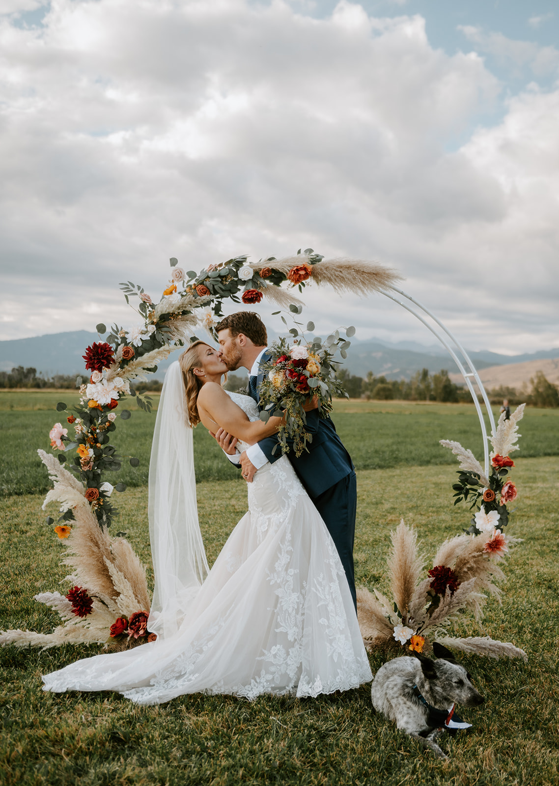 Bride and groom kissing under country chic circular altar at the base of the wallowa mountains