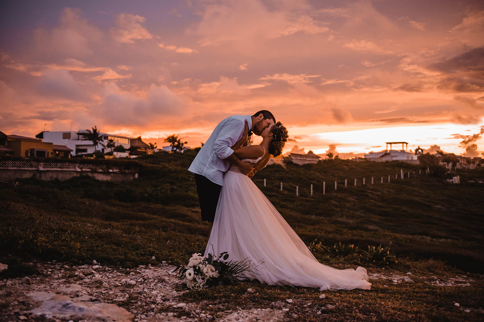 Bride and groom kissing under the pink sunset on Isla Mujeres