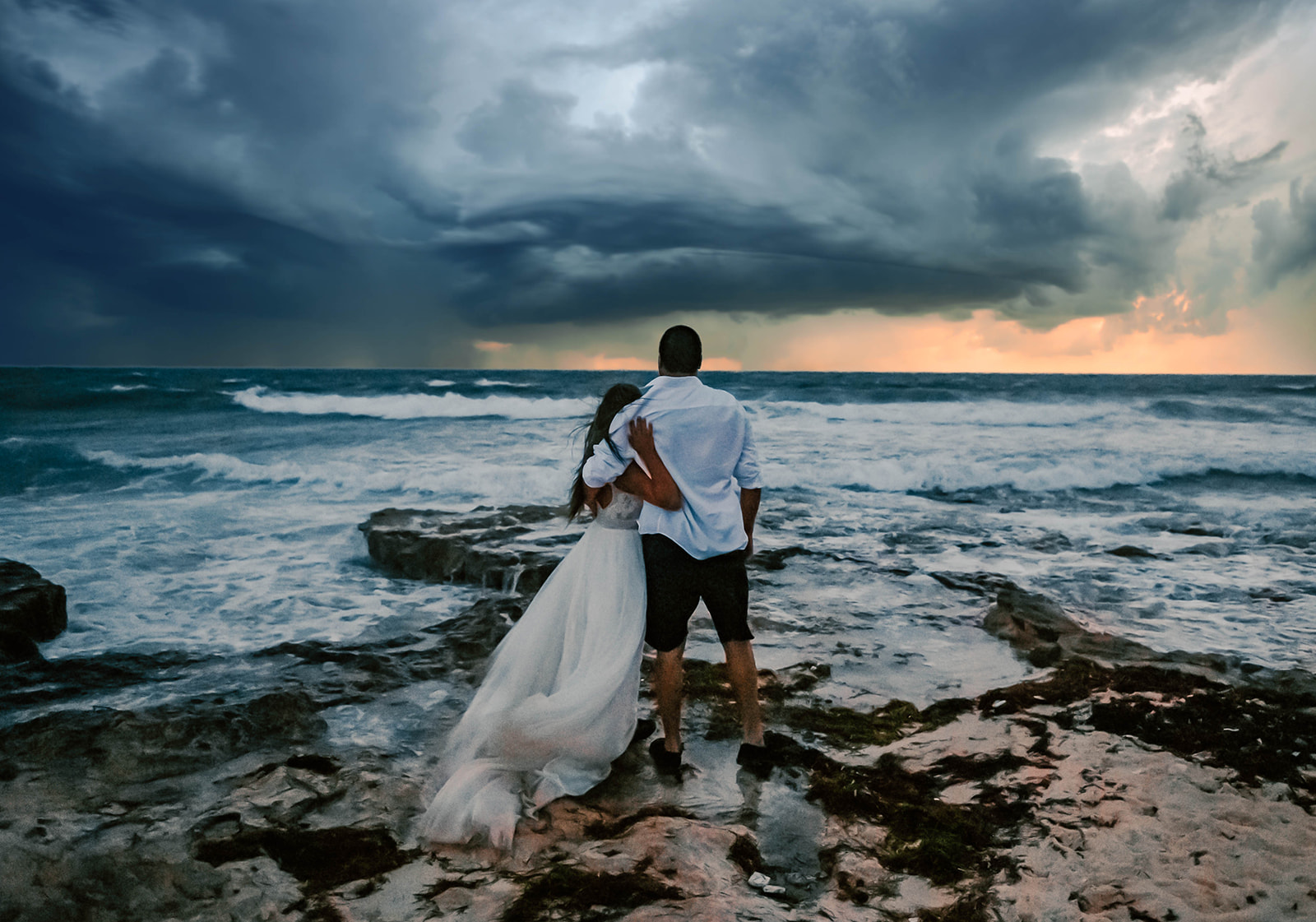 Bride and groom staring over the caribbean sea during a hurricane