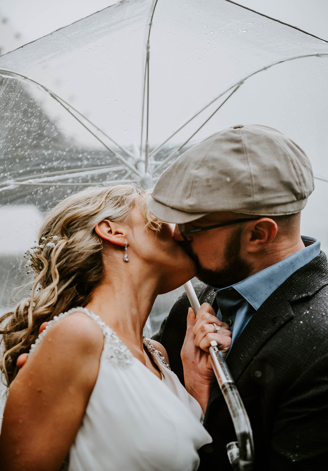 A bride and groom kissing underneath a clear umbrella during their winter wedding on the Oregon Coast.