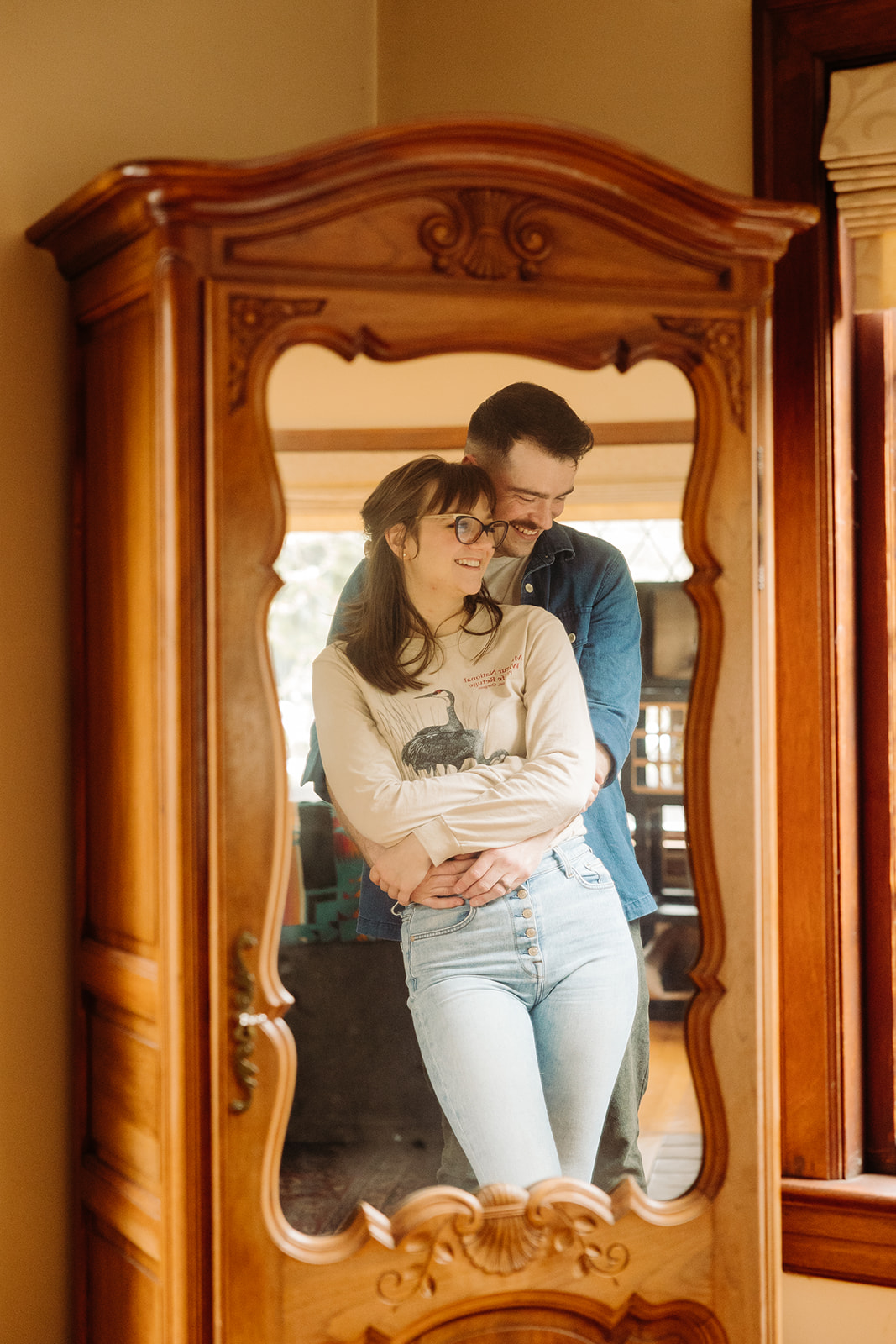 Couple poses in front of a mirror during their at home engagement photo session