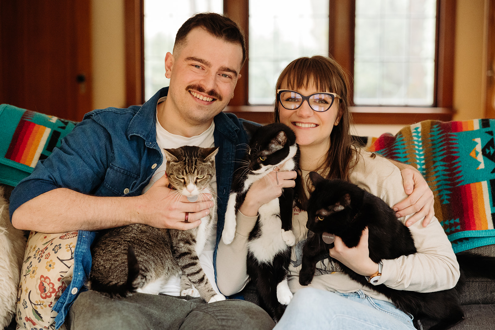 Couple holds all their cats for a family photo during their at home engagement photo session