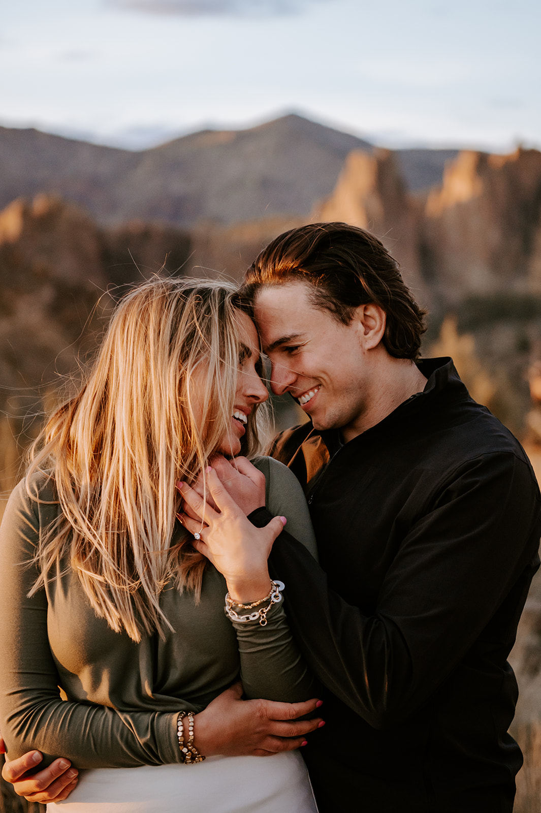 Newly engaged couple face to face smiling at smith rock
