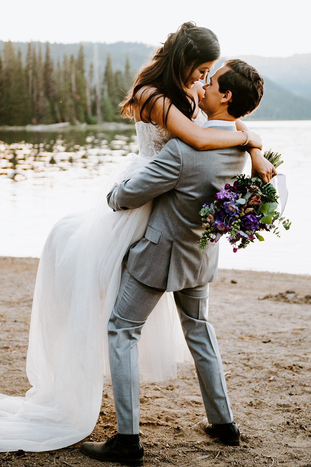 Groom holding bride while they look in each others eyes at sparks lake 