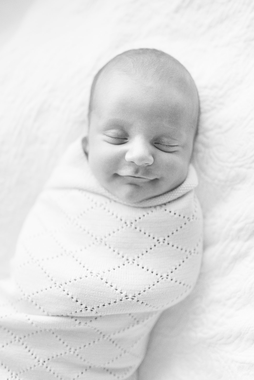 Black and white photo of newborn baby boy wrapped in swaddle