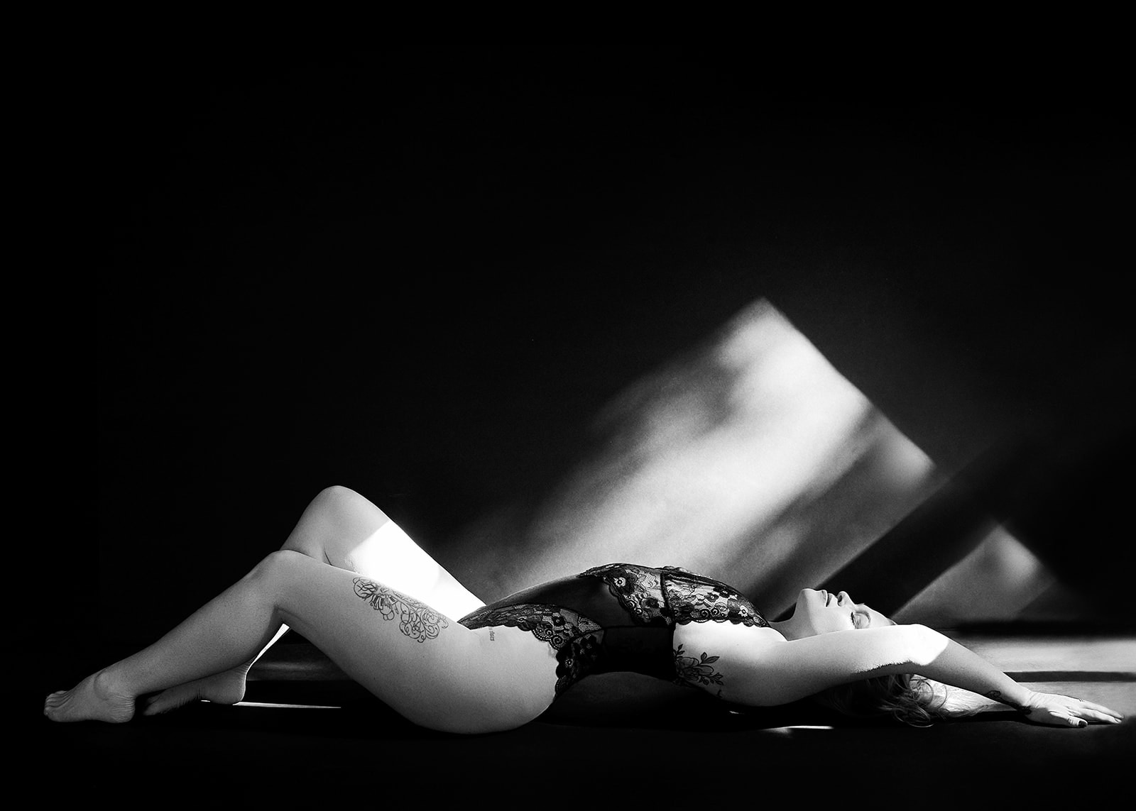 Woman in black lingerie laying in the sun for a boudoir photograph