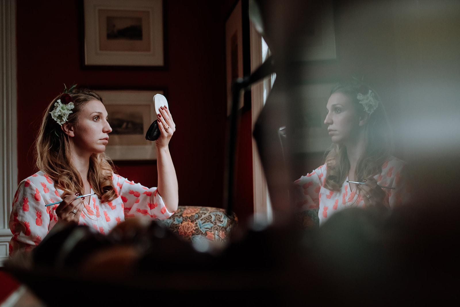 Bride and her reflection while she holds up a compact to look in the mirror.