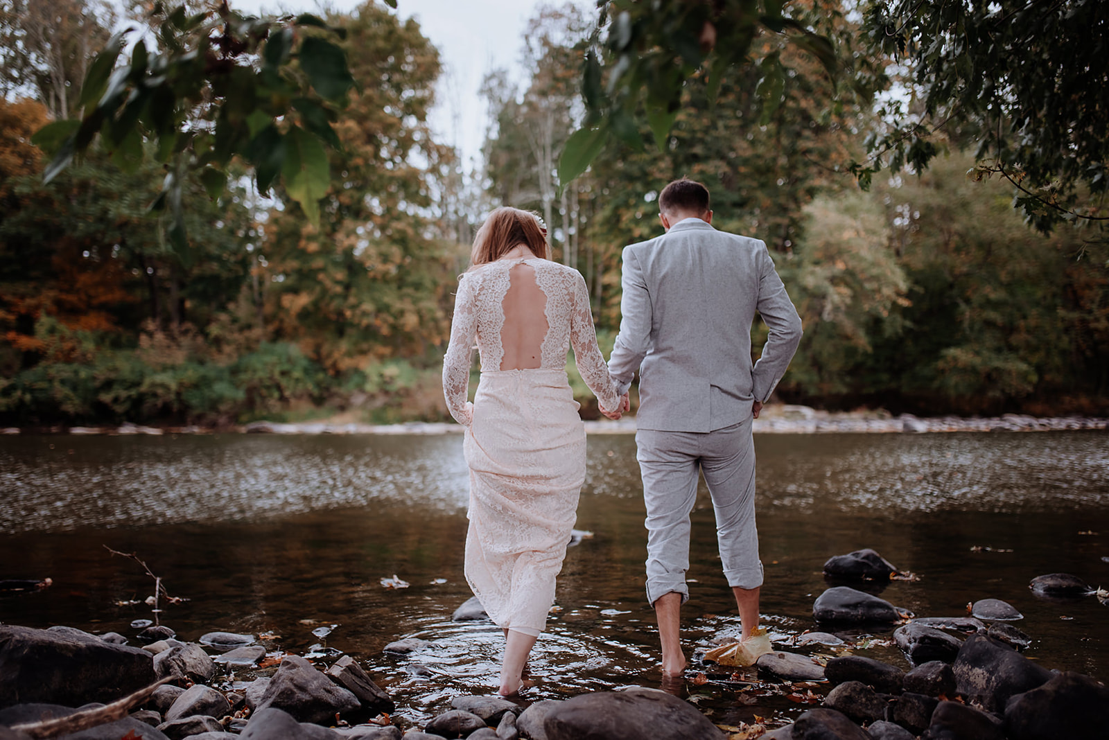 Couple holds hands and wades into river for romantic pictures before their wedding.