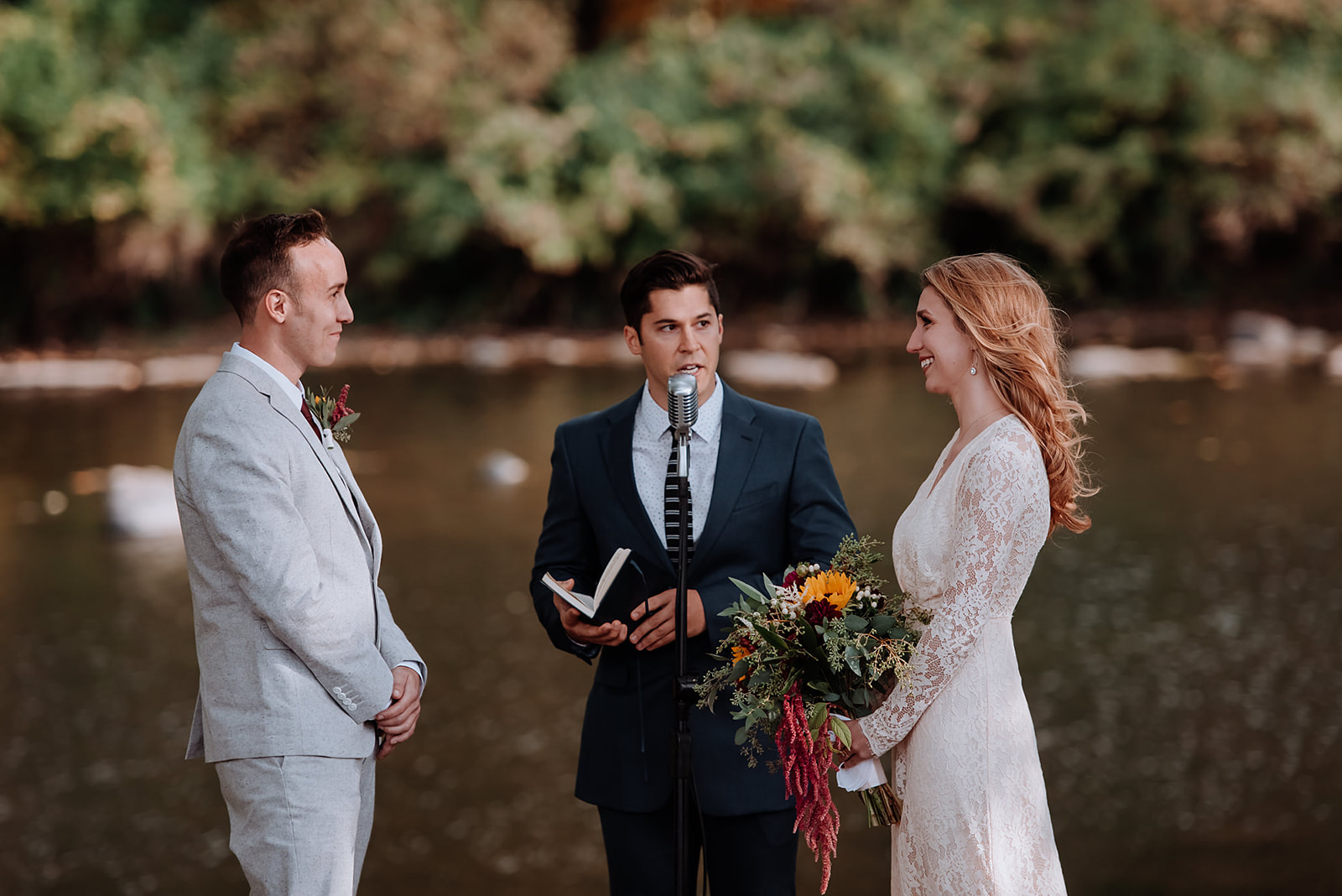 Couple's friend officiates their wedding ceremony along the rivers edge at Hudson Valley Barn wedding.
