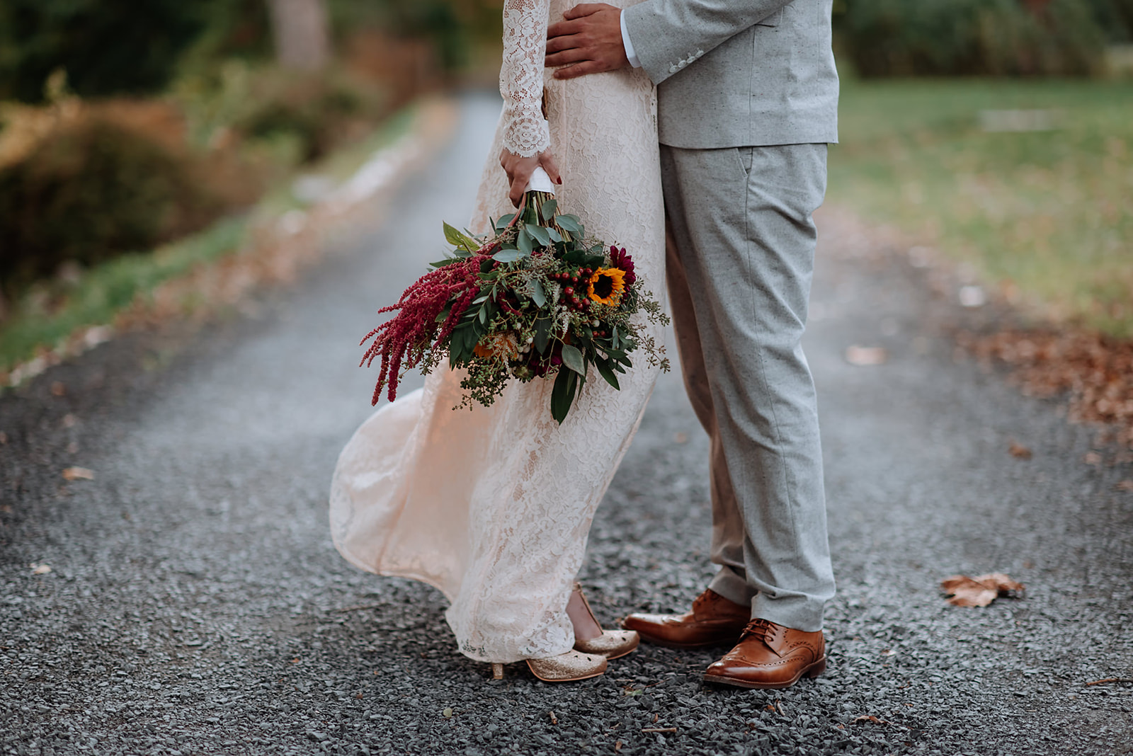 Up close image of couples legs with bride holding her bouquet and dress blowing in the wind.