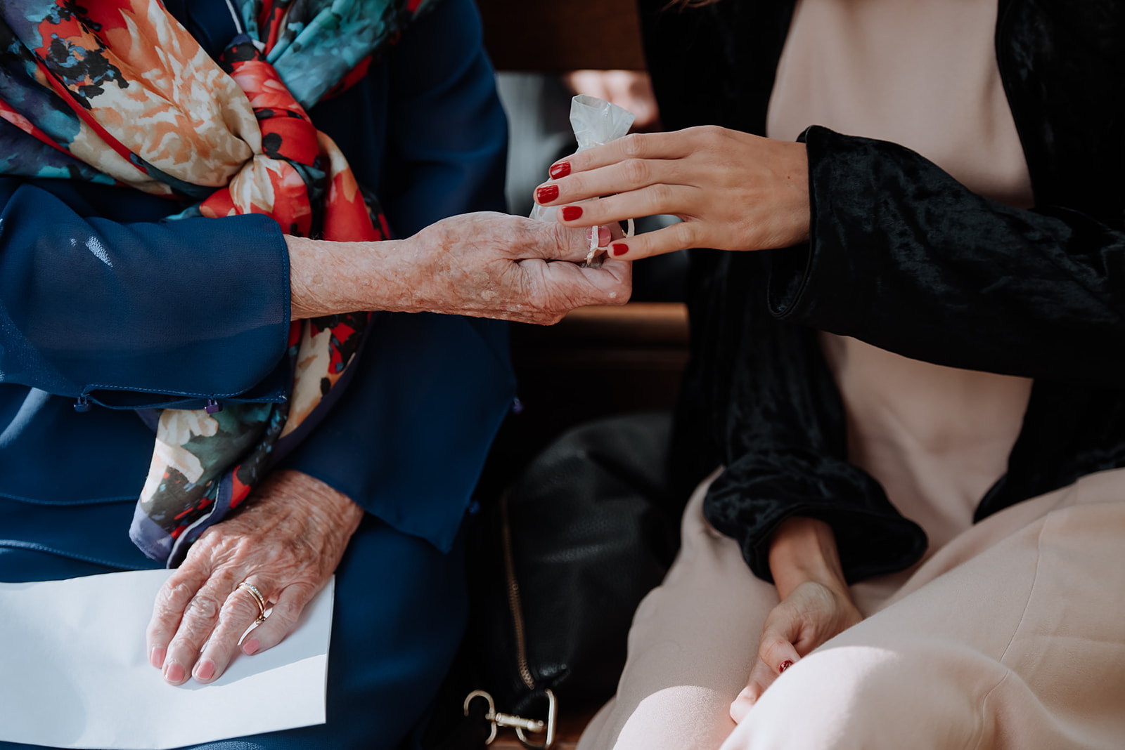 Up close of two older women's hands passing a linen pouch during the Ring Passing ceremony.