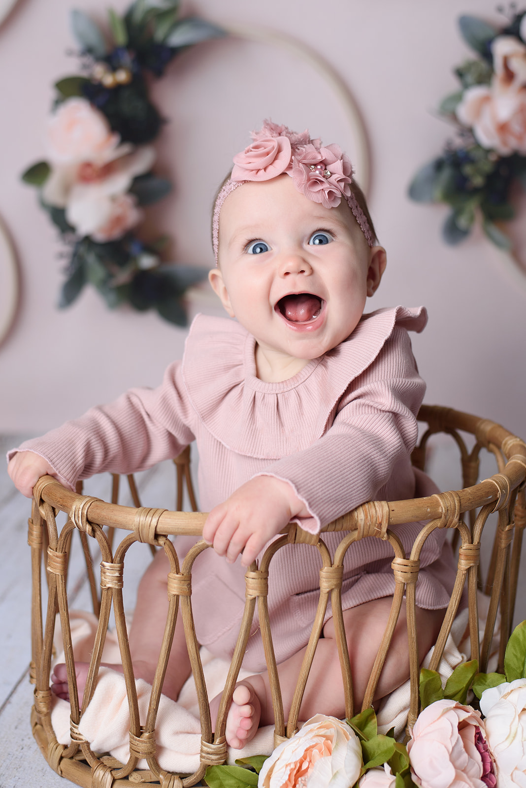 A baby girl sits in a basket and smiles during her milestone session with Rachel Mummert Photography in Hanover, PA