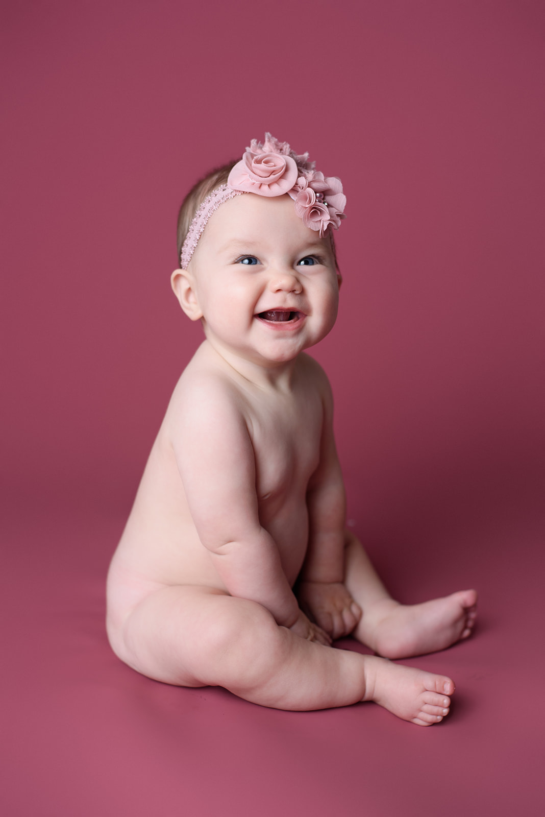 A baby girl giggles during her 6 month milestone photography session with Rachel Mummert Photography