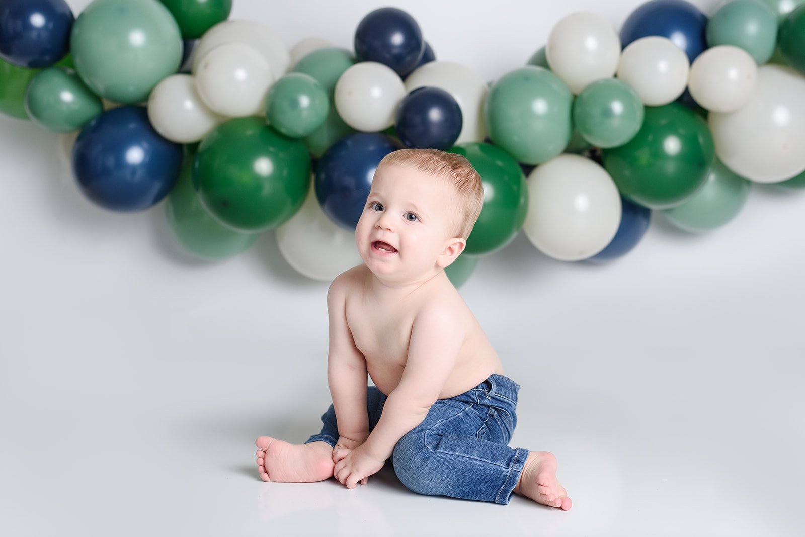 balloons fill the background as a baby celebrates turning one year old