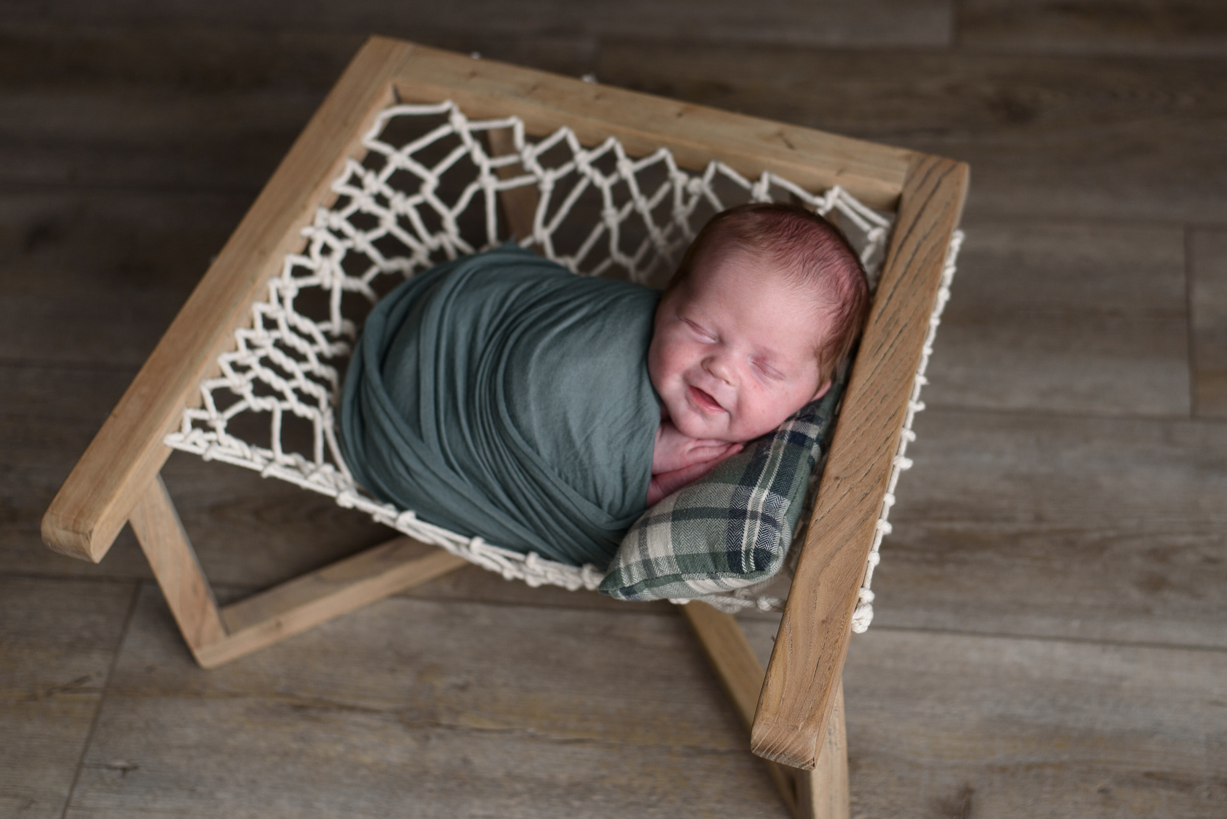 Newborn baby boy relaxes in a prop during his newborn session with Rachel Mummert Photography