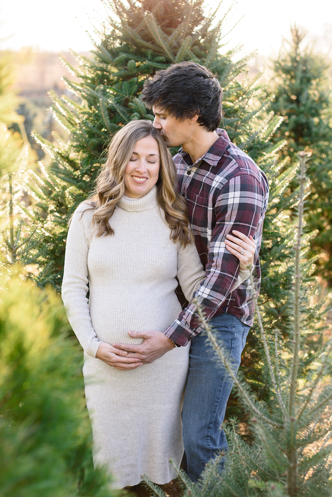 Soon-to-be parents snuggle in the Christmas trees during their maternity photoshoot with Rachel Mummert Photography