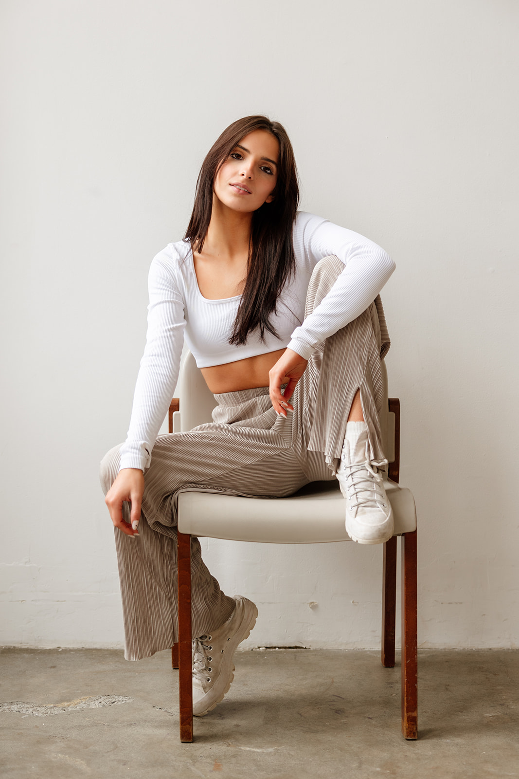 Fashionable portrait of a teen girl sitting in front of a white backdrop inside a Seattle natural light photo studio.