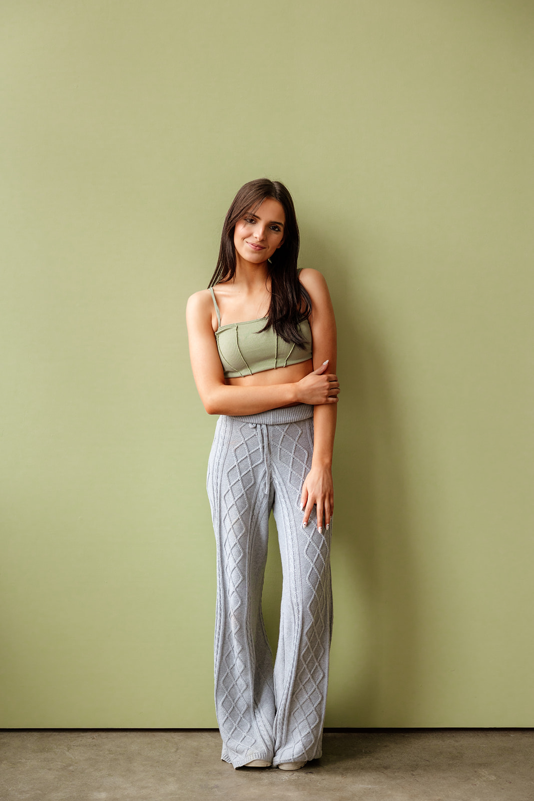 Full-body photo of a teen girl fashionably dressed in front of an olive green backdrop in a Seattle studio.
