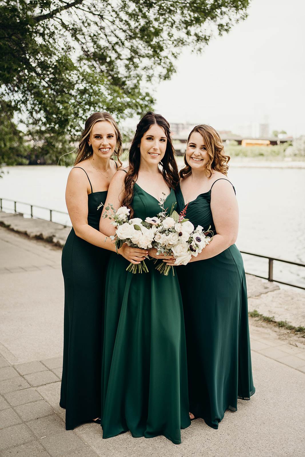 Bridesmaids in green holding their bouquets in front of each other.