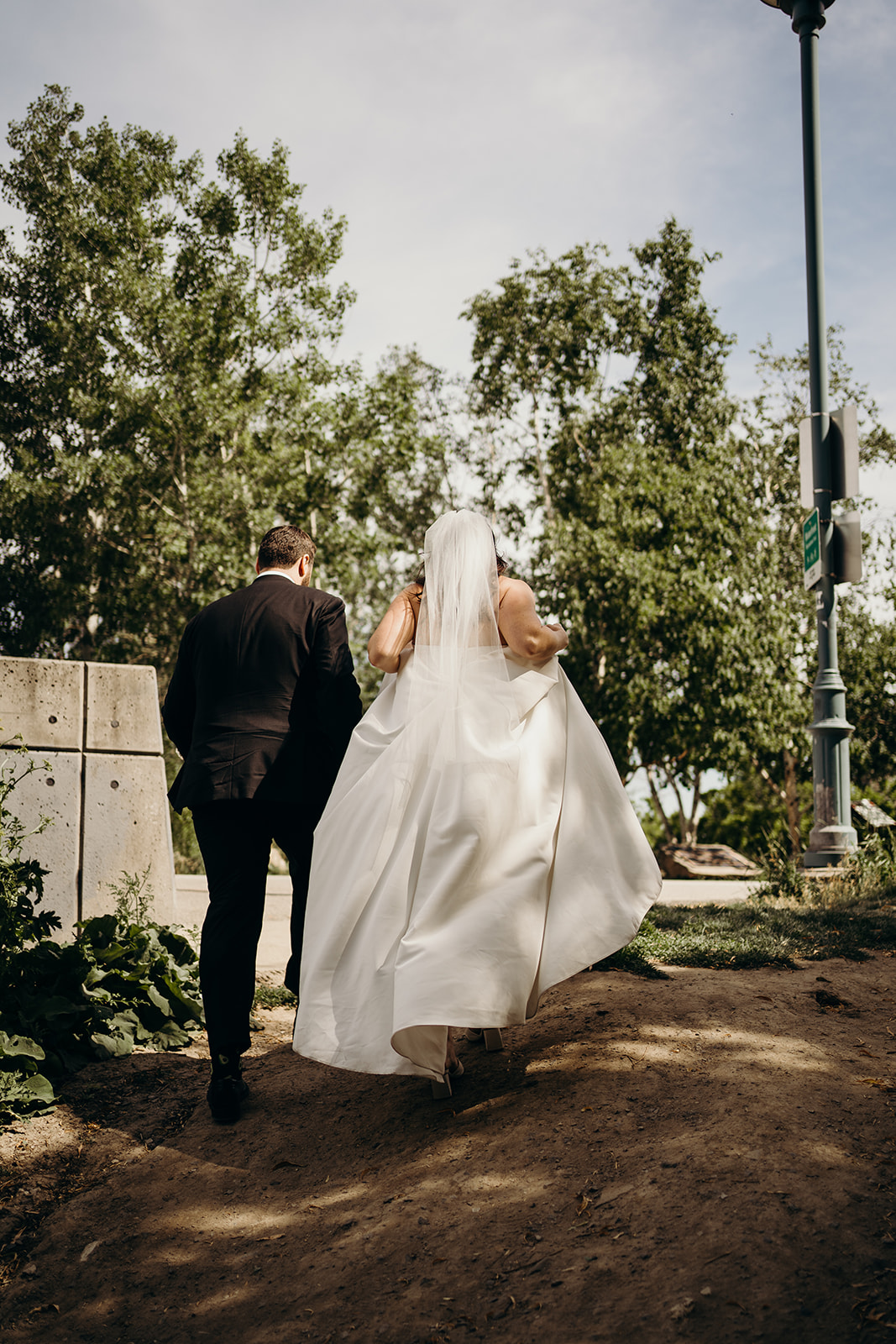 Husband and wife walking up a hill while the wife holds her dress.