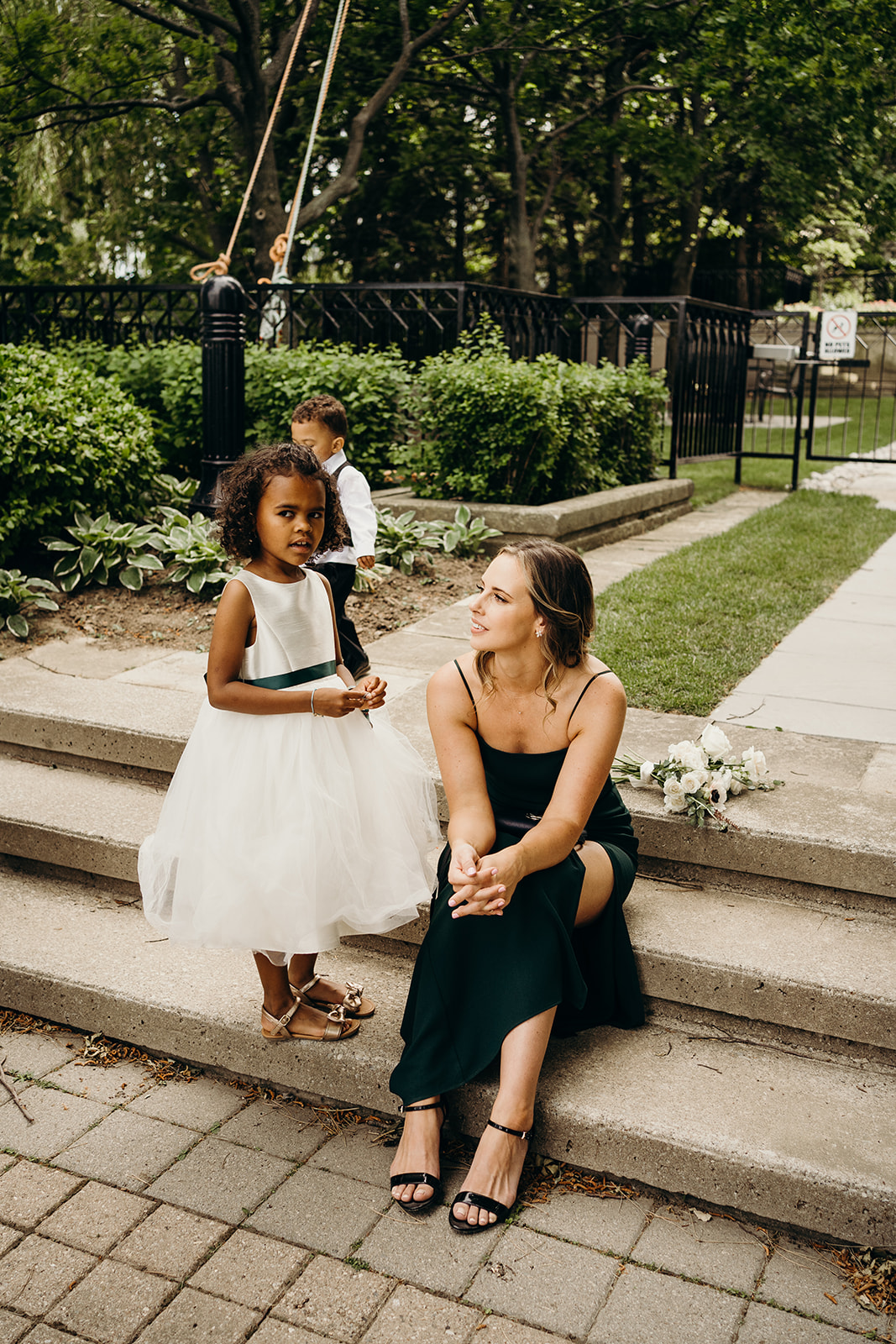 A lady talking to a child standing in a white dress.