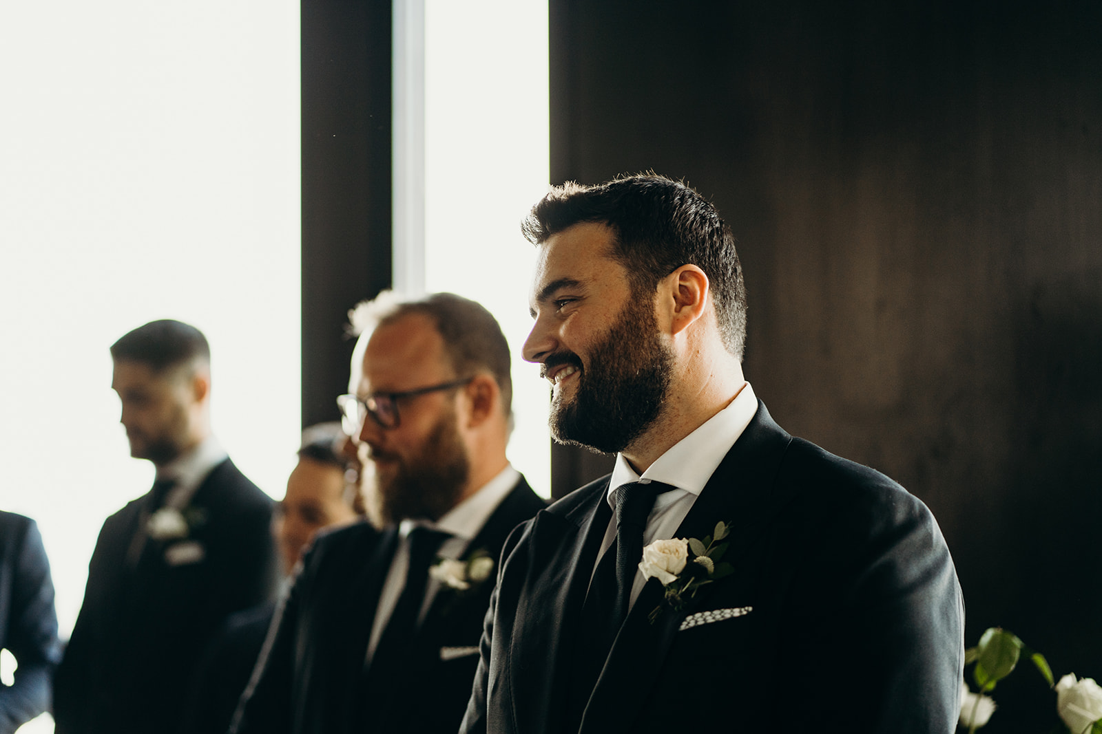 A man in a tux smiling at someone.