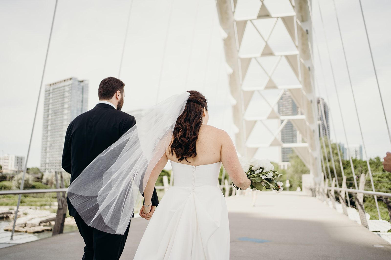 Married couple walks down the bridge together holding hands.